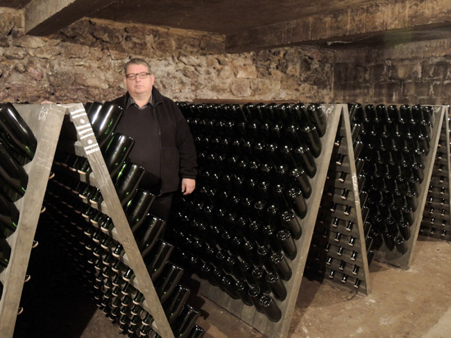 François Godart in his cellar where his divine bottles rest on racks.